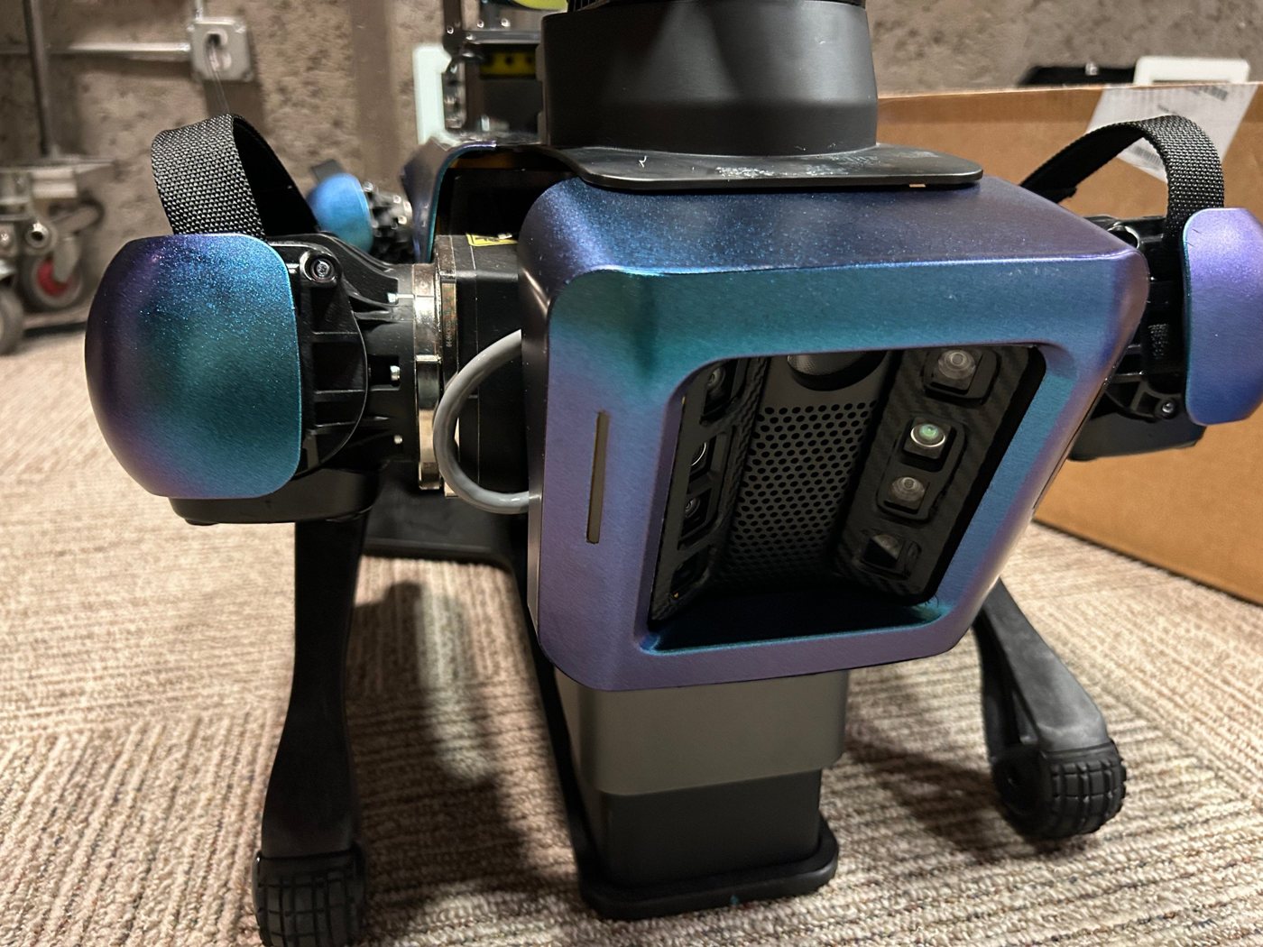 Close-up of one of our robots, its body and hip covers wrapped in color-shifting blue and violet vinyl, with its camera array facing forward